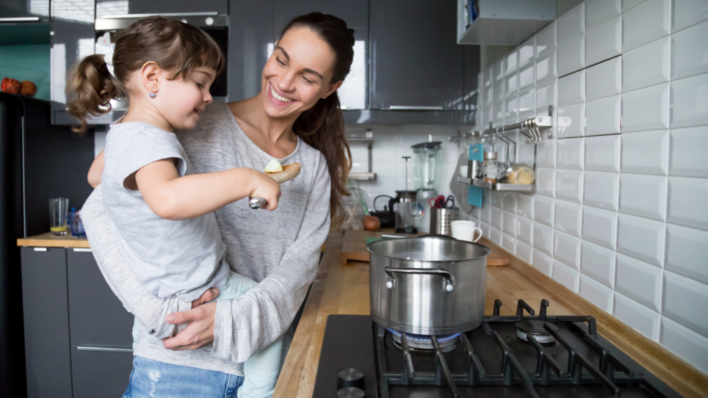 A mother and daughter, laughing and cooking together in the kitchen, sharing nutrition hacks for busy moms