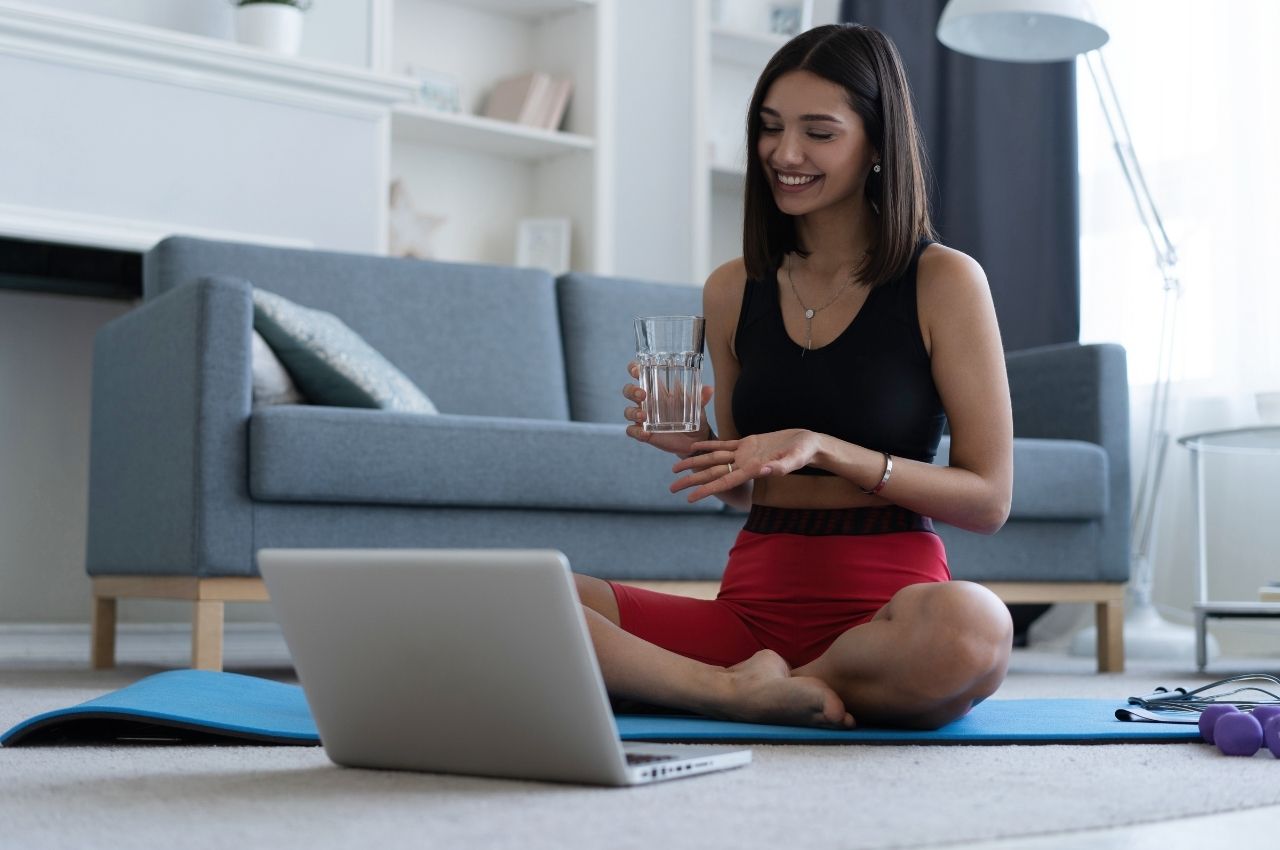 Workout tips for busy moms: Mom sitting in front of her laptop on a yoga mat