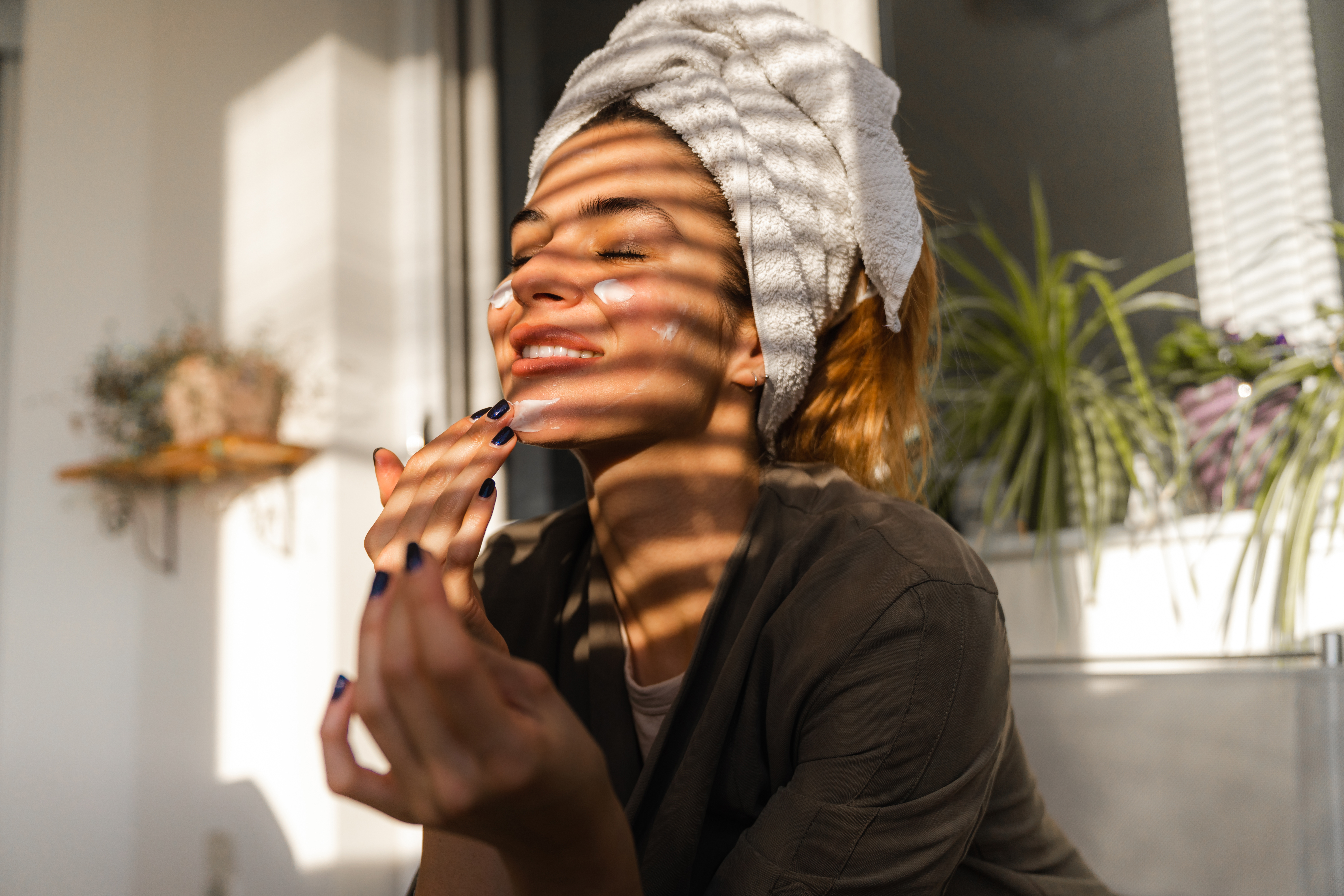 Woman in beautifully lighting applying a face mask