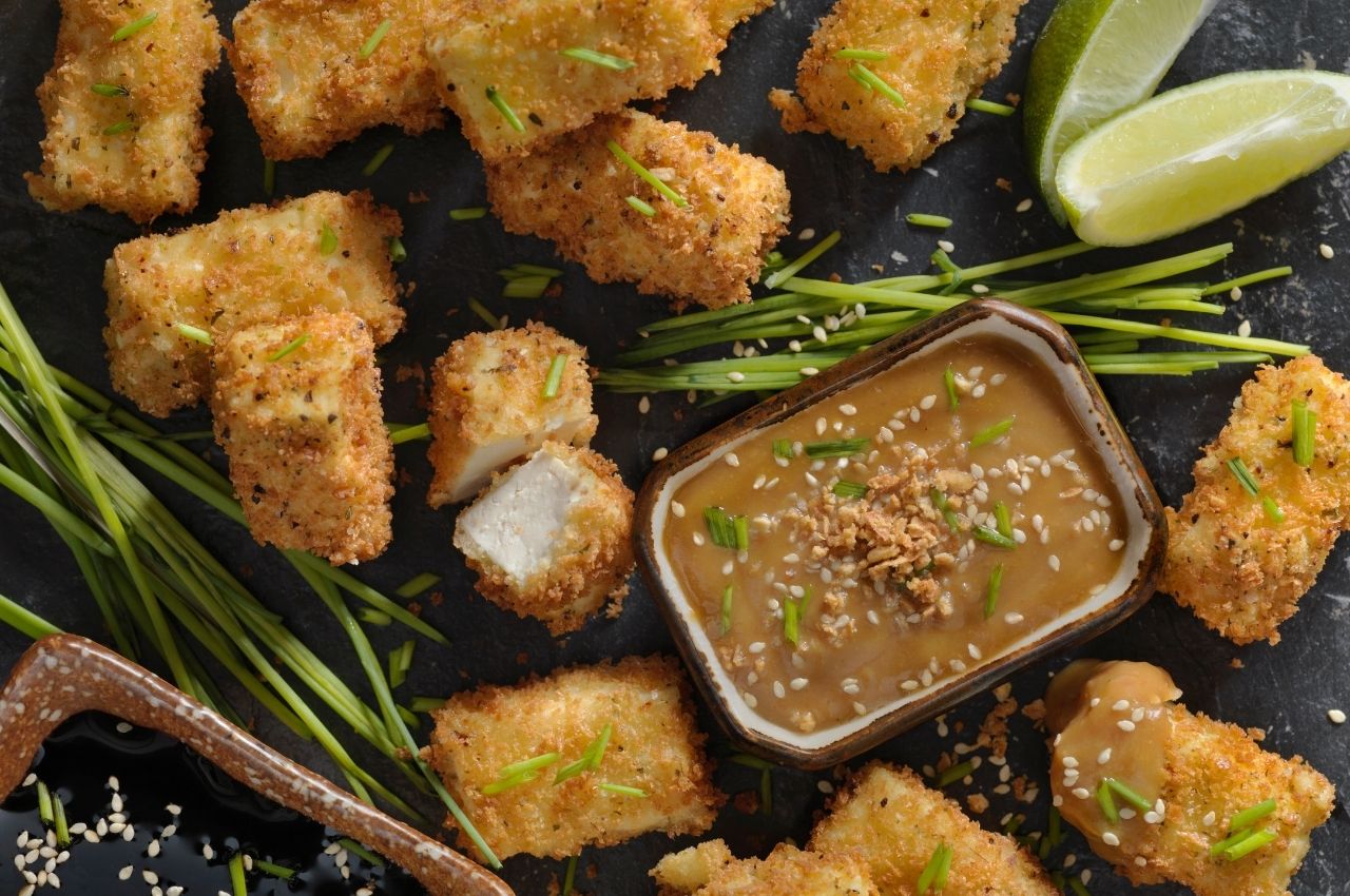 A plate of fried tofu bites with limes and peanut sauce as a plant-based high protein snack