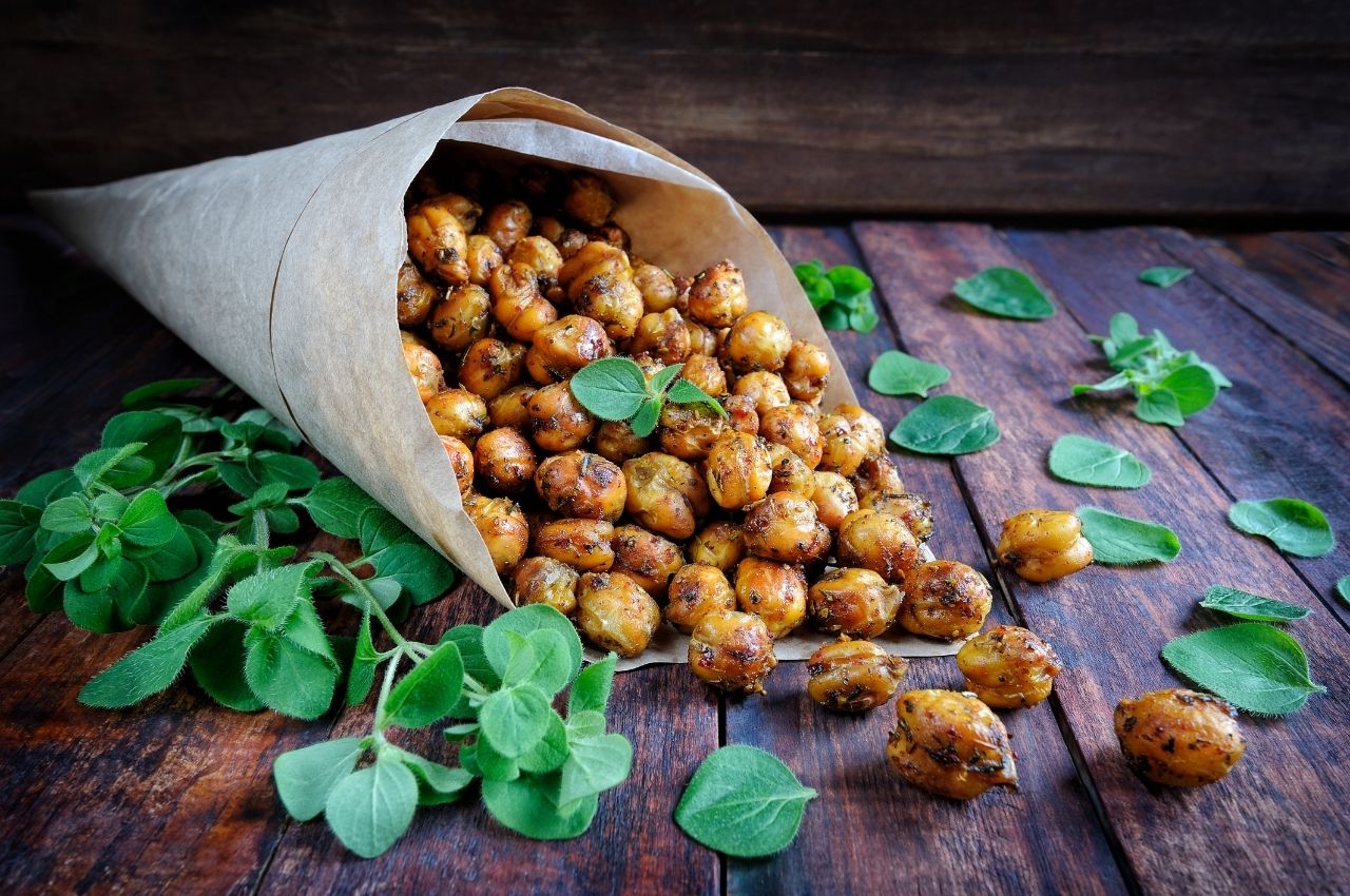 A paper cone of spicy baked chickpeas with green coriander leaves around it