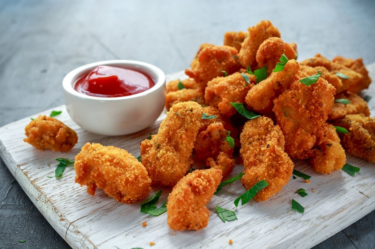 This High-Protein Snack is Chicken Nuggets with a bit of Ketchup on a wooden plate