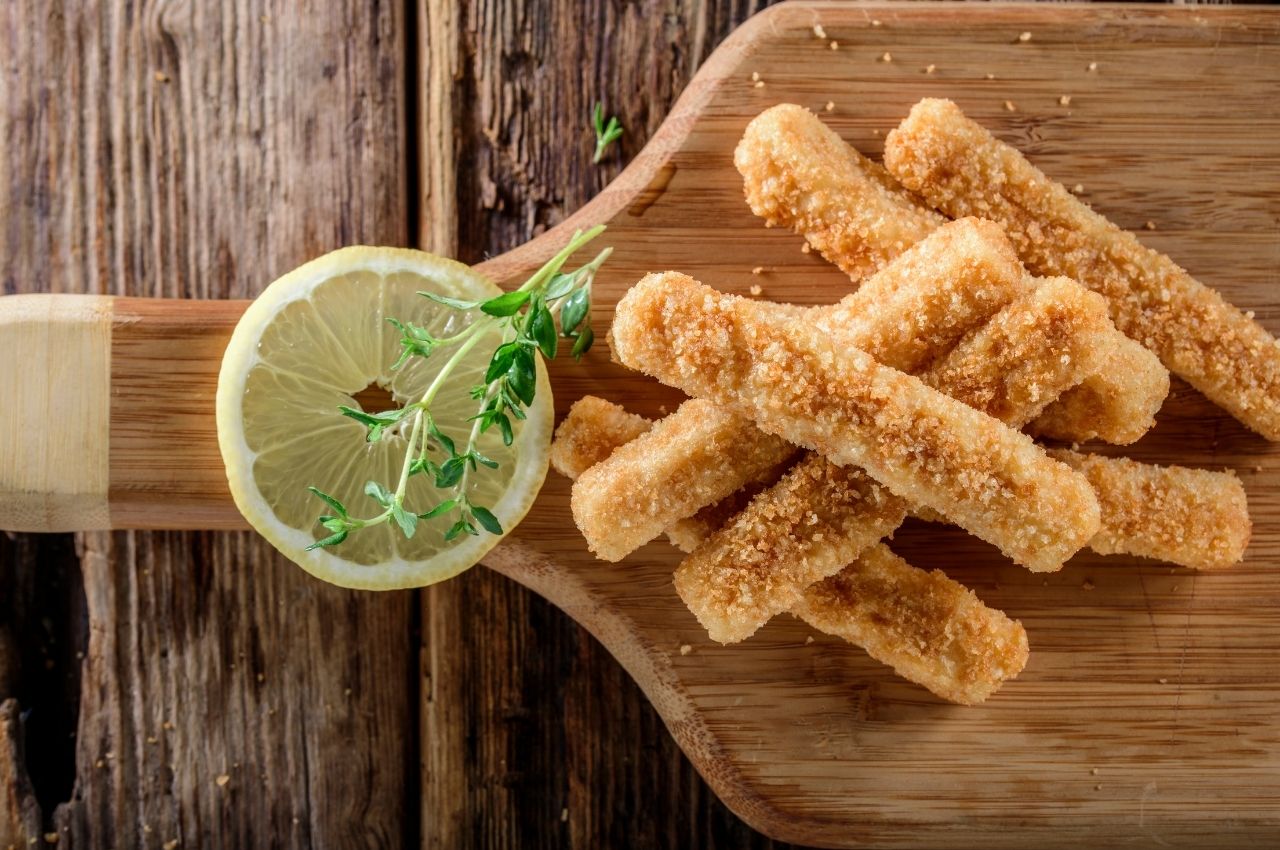 Fish sticks with a slice of lemon on a cutting board as an example of high-protein recipes